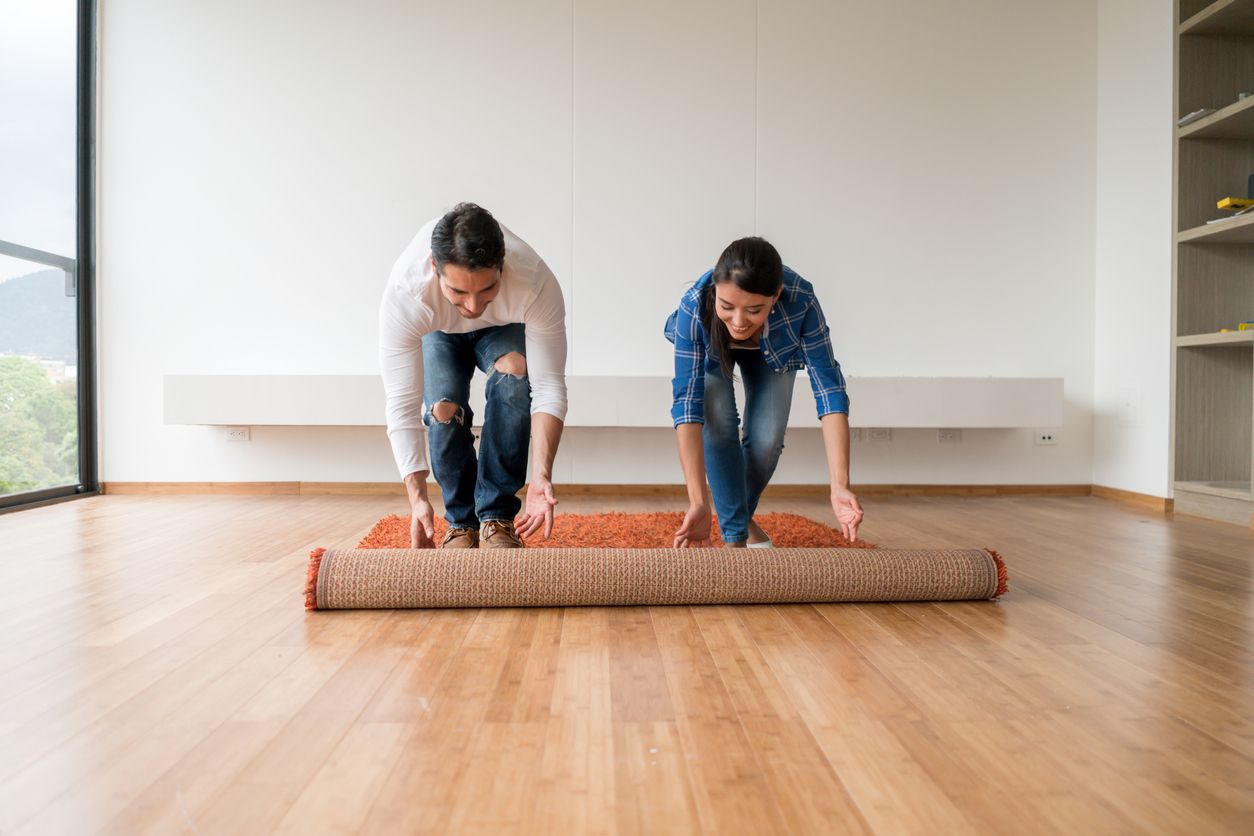 Couple unrolling a rug onto their new bamboo flooring