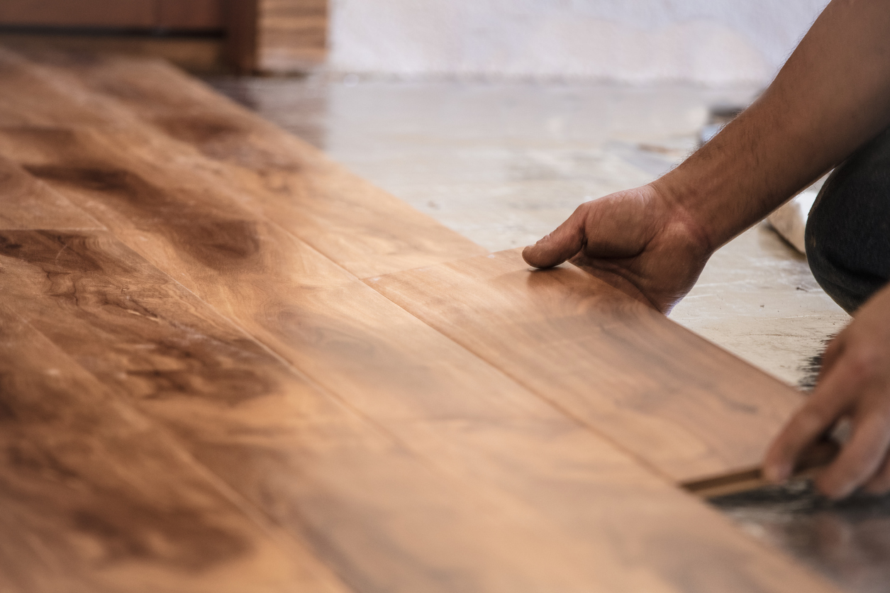 man installing wood floors with extra flooring for cutting