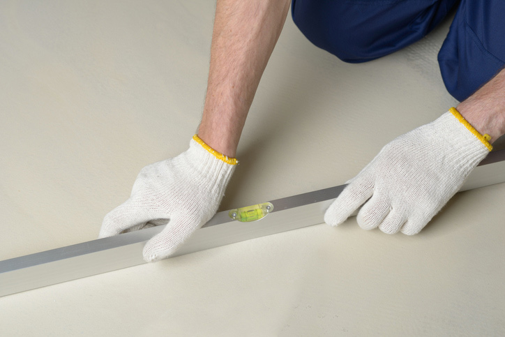 Construction worker measures the quality of floor using spirit level