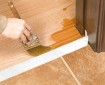 Painter Brushing Clear Polyurethane staining on Hardwood Floor