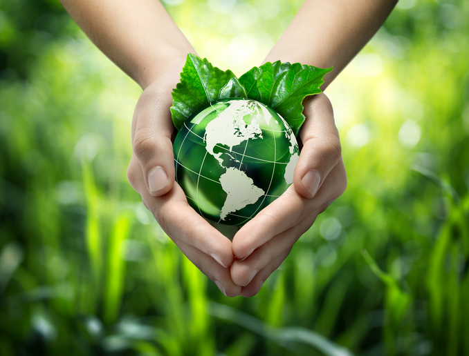 Hands holding green globe with grassy background for green living concept