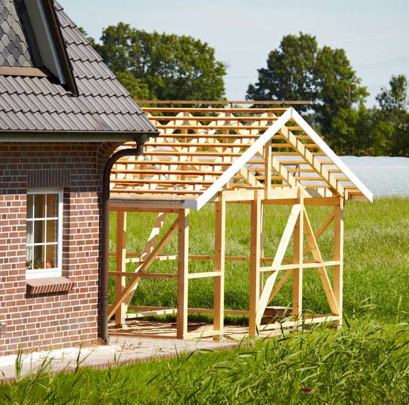 Close up of a part of a family home. Green landscape in background. On the right side you can see a new wooden scaffolding or frame