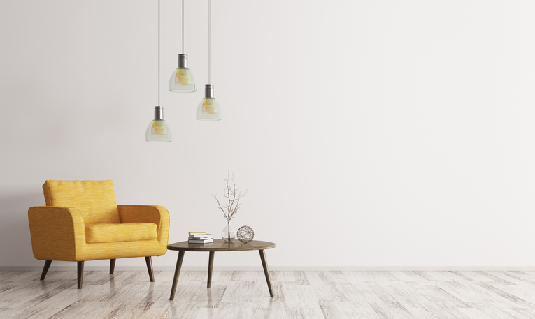 Interior of living room with wooden triangular coffee table, lamps and yellow armchair and bamboo flooring