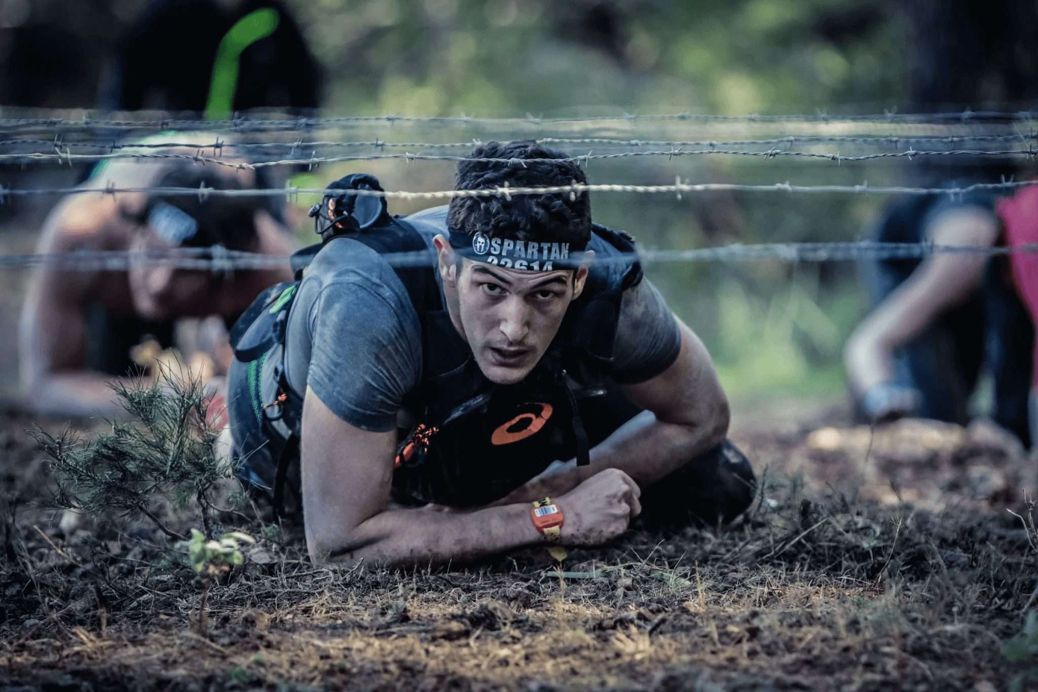 Man crawling under barbed wire in the Spartan Race