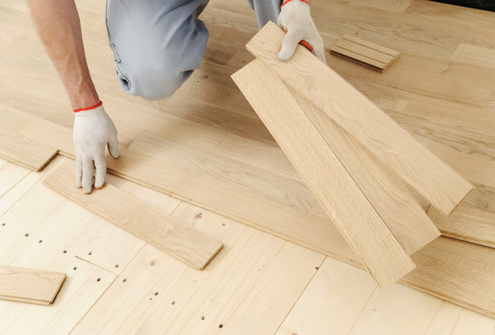 Laying hardwood parquet. Worker decides the direction and fixes the boards one by one.