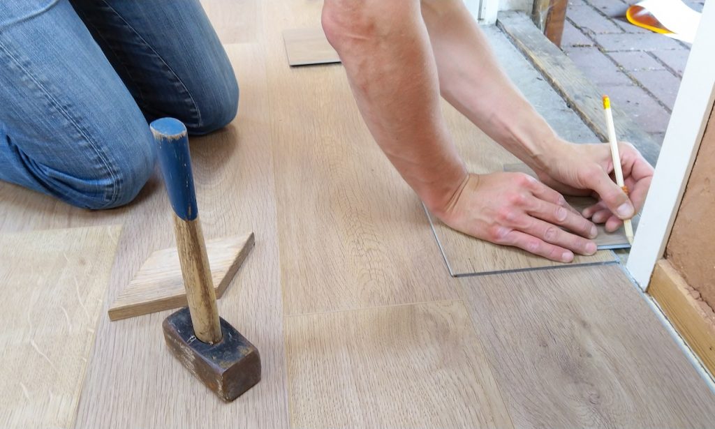 A man installs new flooring over one of five types of subfloor.