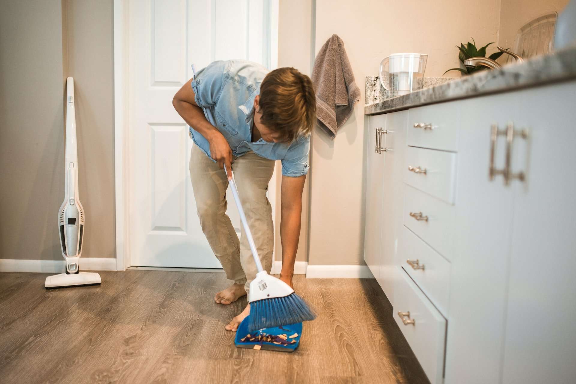 A man using a microfiber broom after learning how to clean vinyl plank flooring.