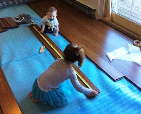 Two children help measure a plank of flooring