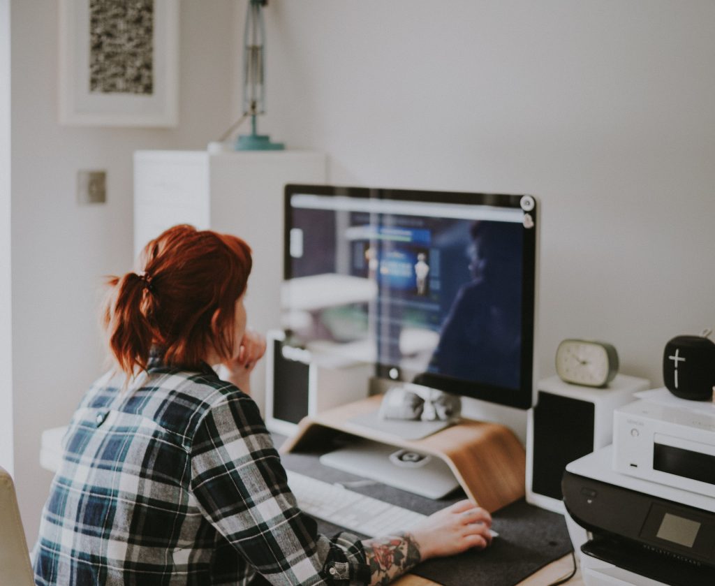 A remote worker sits in an office that melds smart technology with a bright home office remodel design to promote productivity in her work area.