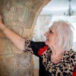 A woman adjusts her thermostat after making affordable renovations to her HVAC system.