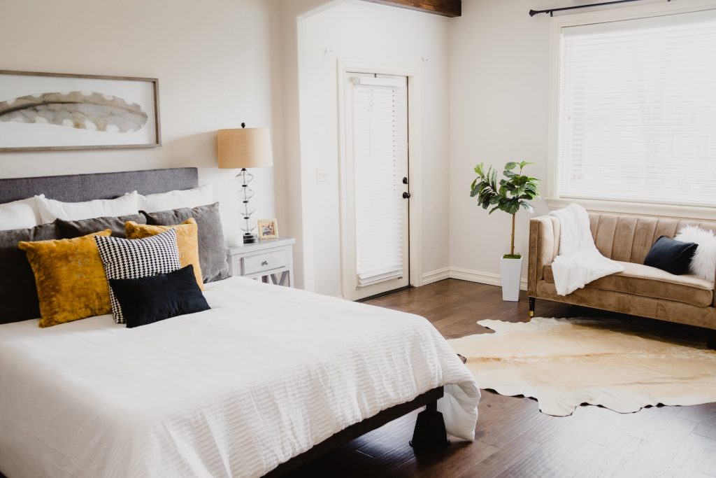 This example of guest bedroom ideas includes a velour sofa and throw rug over eucalyptus plank flooring.