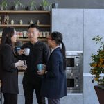 Three employees using personal drinking mugs in the kitchen for a more sustainable office.