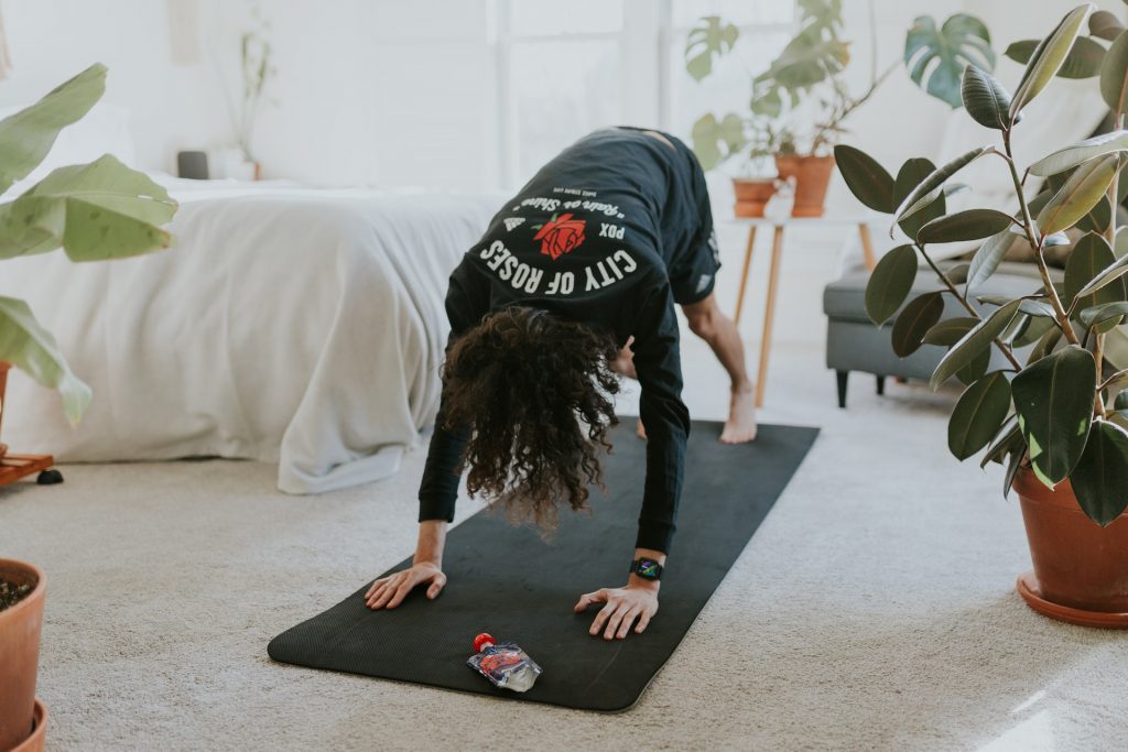 A woman exercises on a mat while enjoying the health benefits of her low-maintenance indoor plants.