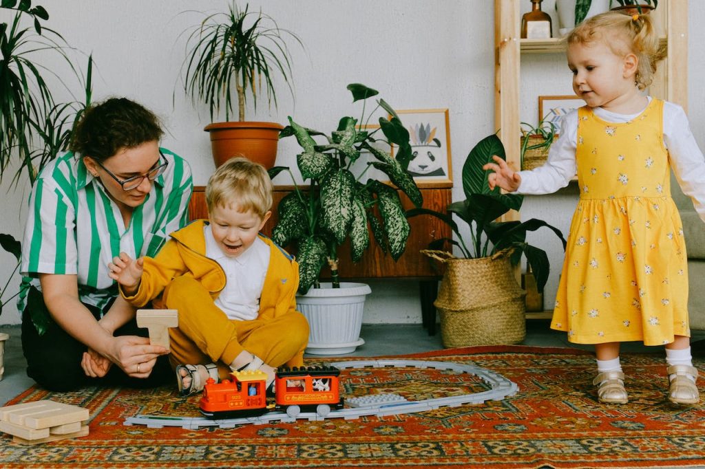 A mother shows a wooden toy to her two small children, ensuring there aren’t common toxins in the home.