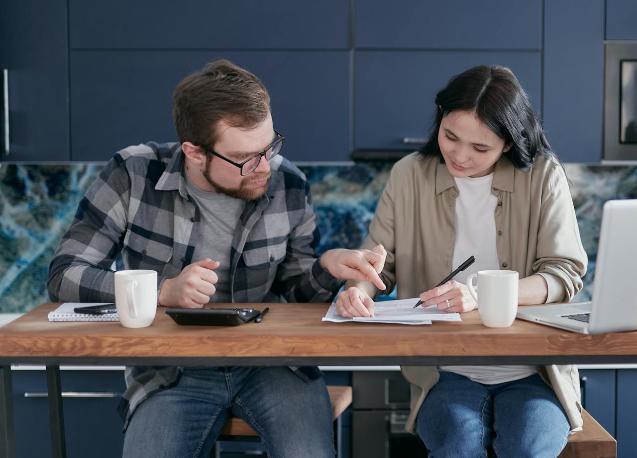 A young couple sits at a table, examining a document and discovering the cost-saving benefits of embracing energy efficiency in their home.