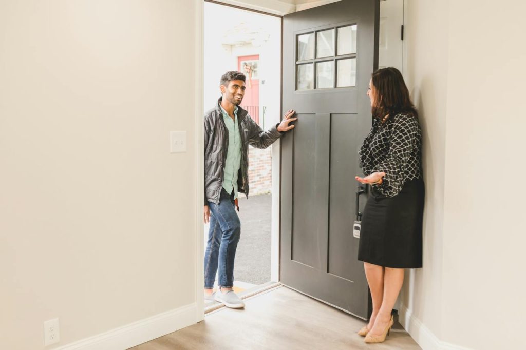A young buyer steps over the threshold, smiling as he tours an energy-efficient home.